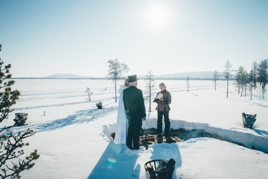 A couple exchanges vows at a sunny wilderness wedding ceremony in Swedish Lapland