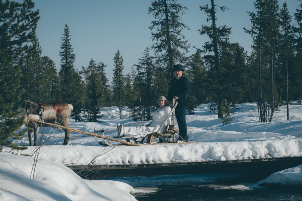 A couple drives a reindeer sled to their wilderness wedding in Swedish Lapland